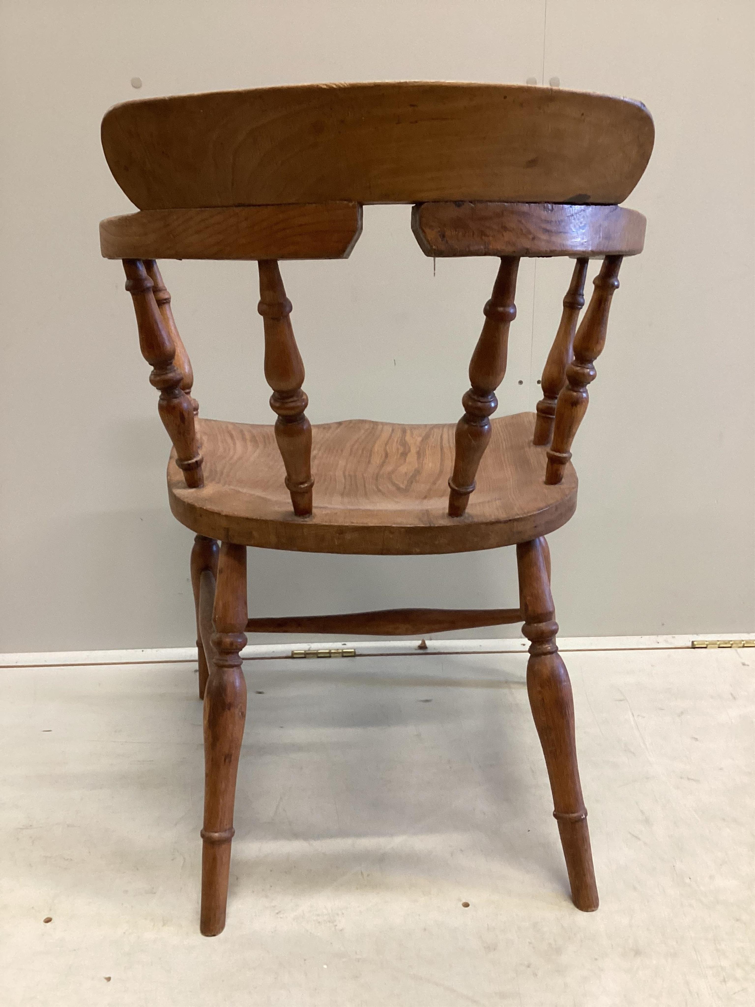 A Victorian elm and beech smoker's bow elbow chair on slender turned baluster legs with H stretcher, width 62cm, depth 45cm, height 78cm. Condition - good, timber slightly faded.